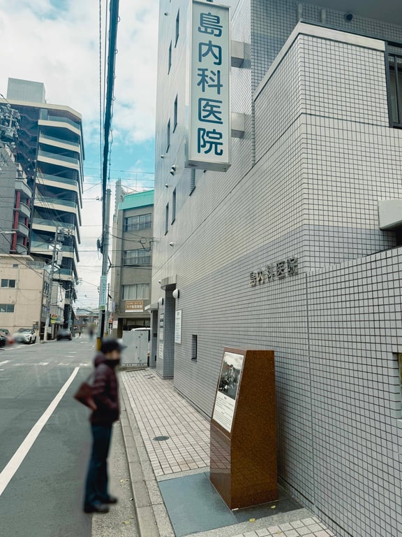 島内科医院と説明板を見ている人
