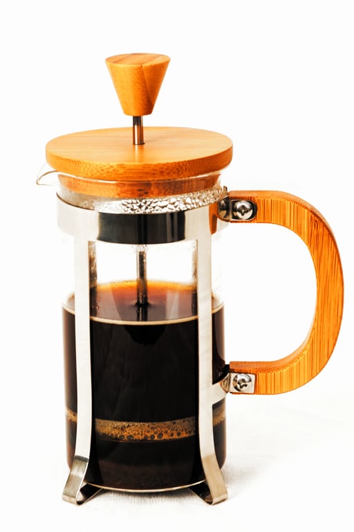 A small French press with a wooden lid and handle, representing the deliberate pressure and distillation process of The Press