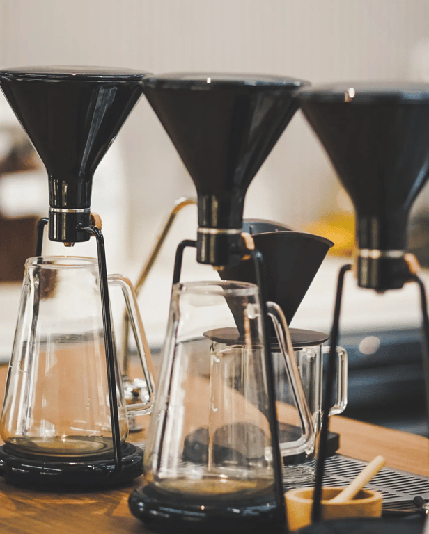 Three pour-over coffee brewers in a row, evoking the deliberate, craft-driven process at the heart of the Pillar & Press methodology