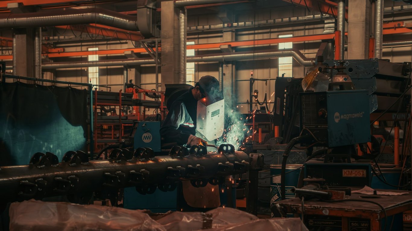 Manufacturing floor: the kind of multi-site rollout work this Quickbase and SharePoint system tracks. Photo by Cemrecan Yurtman on Unsplash
