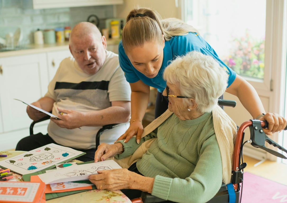Automating weekly CRM reports for a senior home care company: caregiver assisting an elderly couple. Photo by Age Cymru on Unsplash