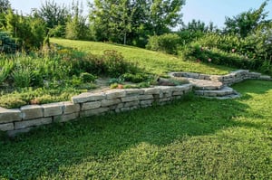The image shows a sloping terrain of a garden. It implies that ground screws can be install in the most difficult of areas because in this case, it can level uneven ground.