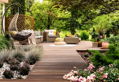 Wooden deck with walkway , surrounded by trees and flowers.