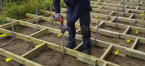 Carpenter building a multi-leveled wooden deck using GroundPlug® Screw Pile Foundations.