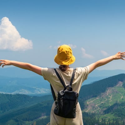 Traveler enjoying panoramic mountain views on a Blue Dot Tours educational adventure, embracing the spirit of exploration and discovery.