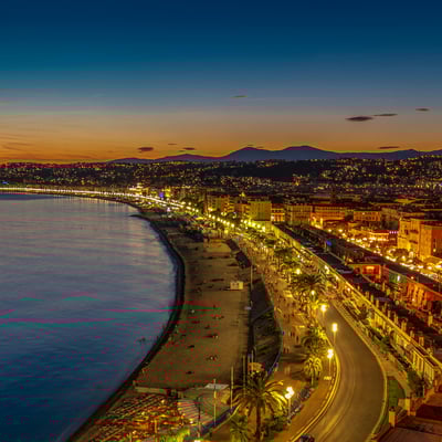 Pebbled beach of Nice lit by streetlights at night