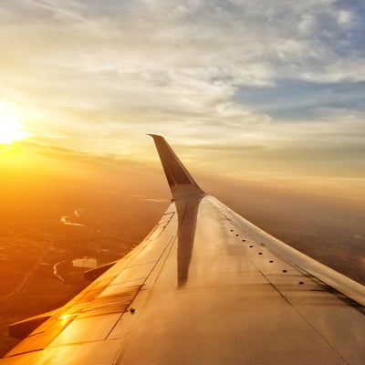 View from an airplane window at sunset, symbolizing the start of the journey and the importance of planning for student safety and on-tour logistics.