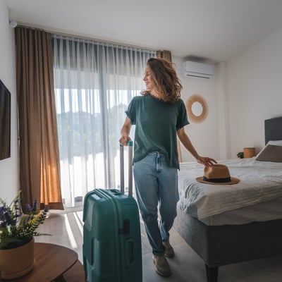 Solo traveler entering a peaceful hotel room with a suitcase, highlighting Blue Dot’s complimentary or discounted single room upgrade for group leaders.