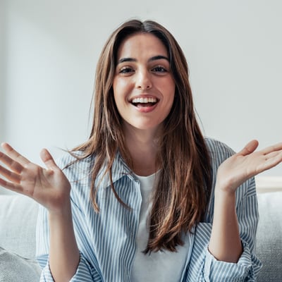 Smiling woman reaching out in a welcoming gesture, representing how easy it is to refer a colleague to Blue Dot and earn travel rewards.