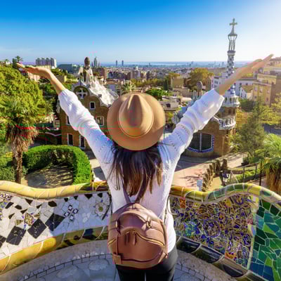 Excited traveler overlooking Barcelona’s Park Güell, celebrating Blue Dot’s lifetime 4x rewards multiplier for tour leaders.
