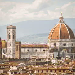 Florence’s Duomo rising above terracotta rooftops with hazy Tuscan hills in the background