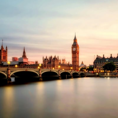 Big Ben and Parliament buildings glowing in the sunset light, reflected in the River Thames