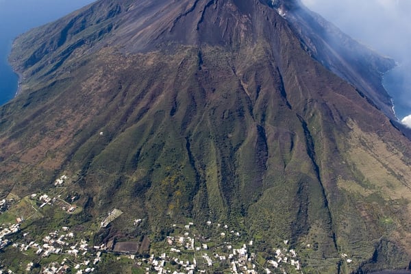 Vista aérea de Stromboli, el volcán activo que se eleva bruscamente del mar con humo saliendo del cráter.