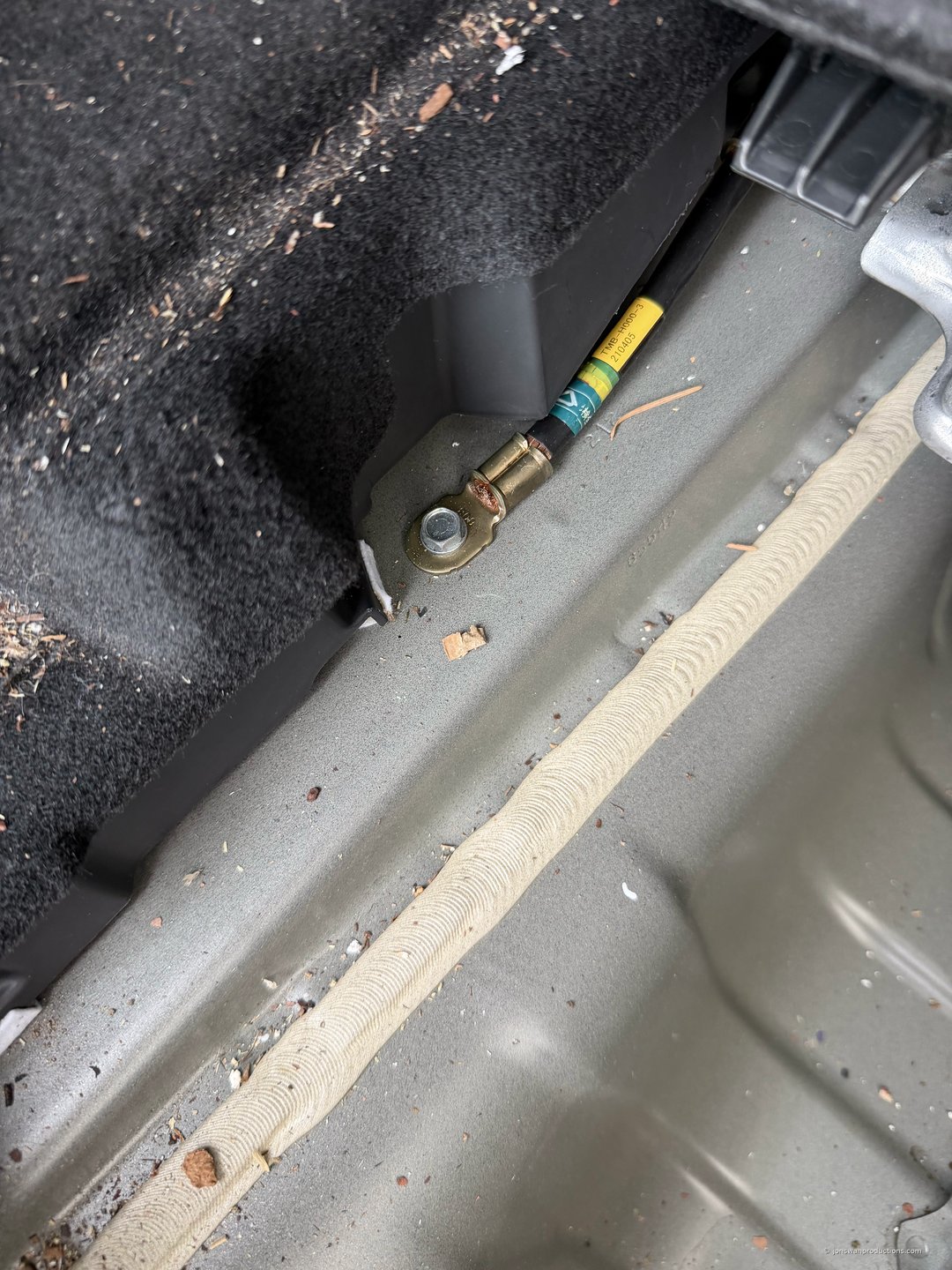 Existing factory ground bolt in a Honda CR-V trunk pan with a ring terminal added beneath it