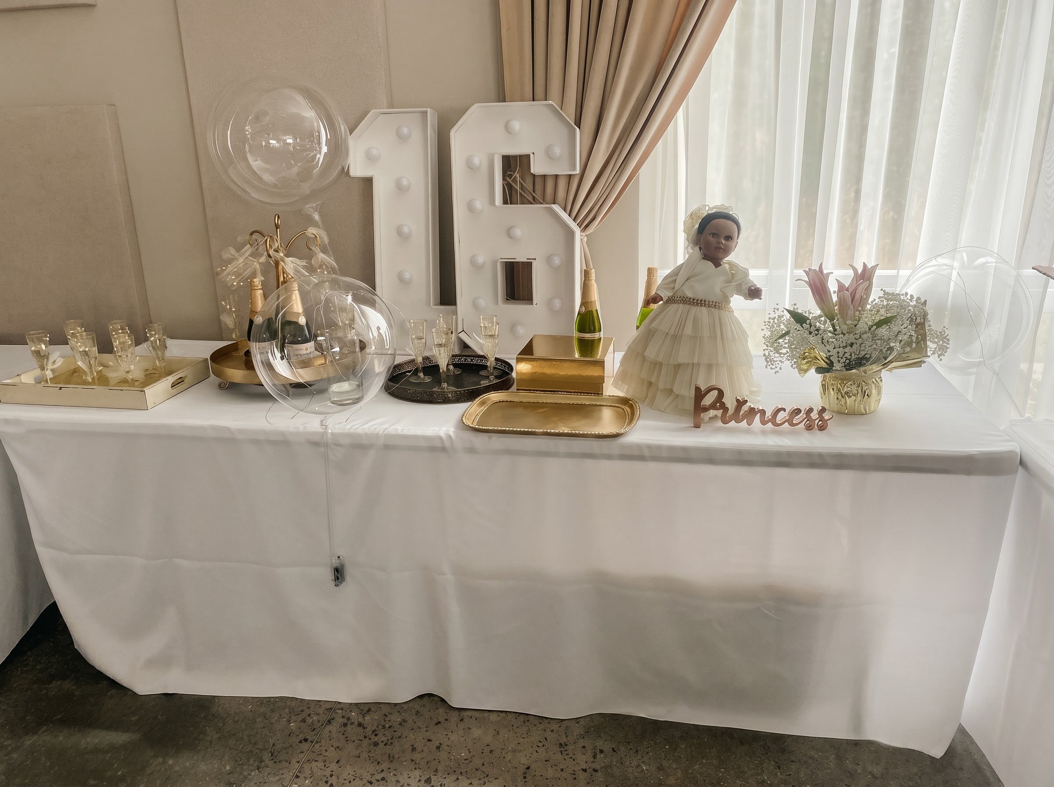 Sweet 16 dessert table with a marquee number sixteen, champagne display and gold accents