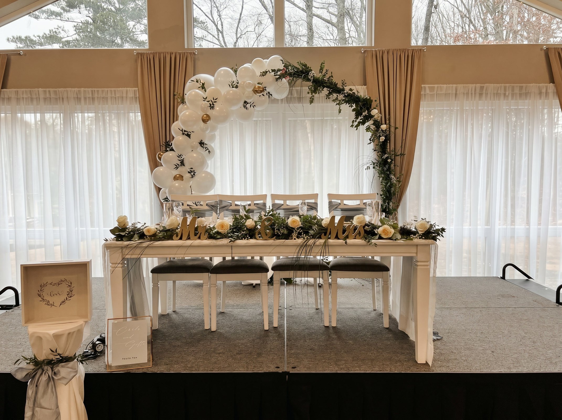 Sweetheart table on the stage framed by a circular balloon and greenery arch