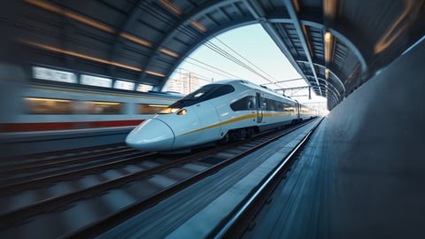Sleek White and Silver High-Speed Train Blurring Past a Platform Desktop Preview