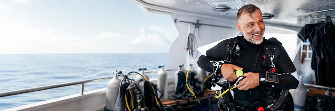 Smiling scuba diver preparing equipment on the back deck of a liveaboard dive boat