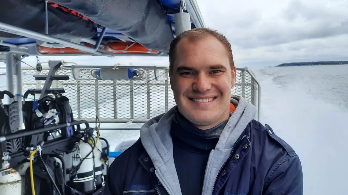 A smiling scuba diver aboard a Sydney dive boat with diving equipment ready