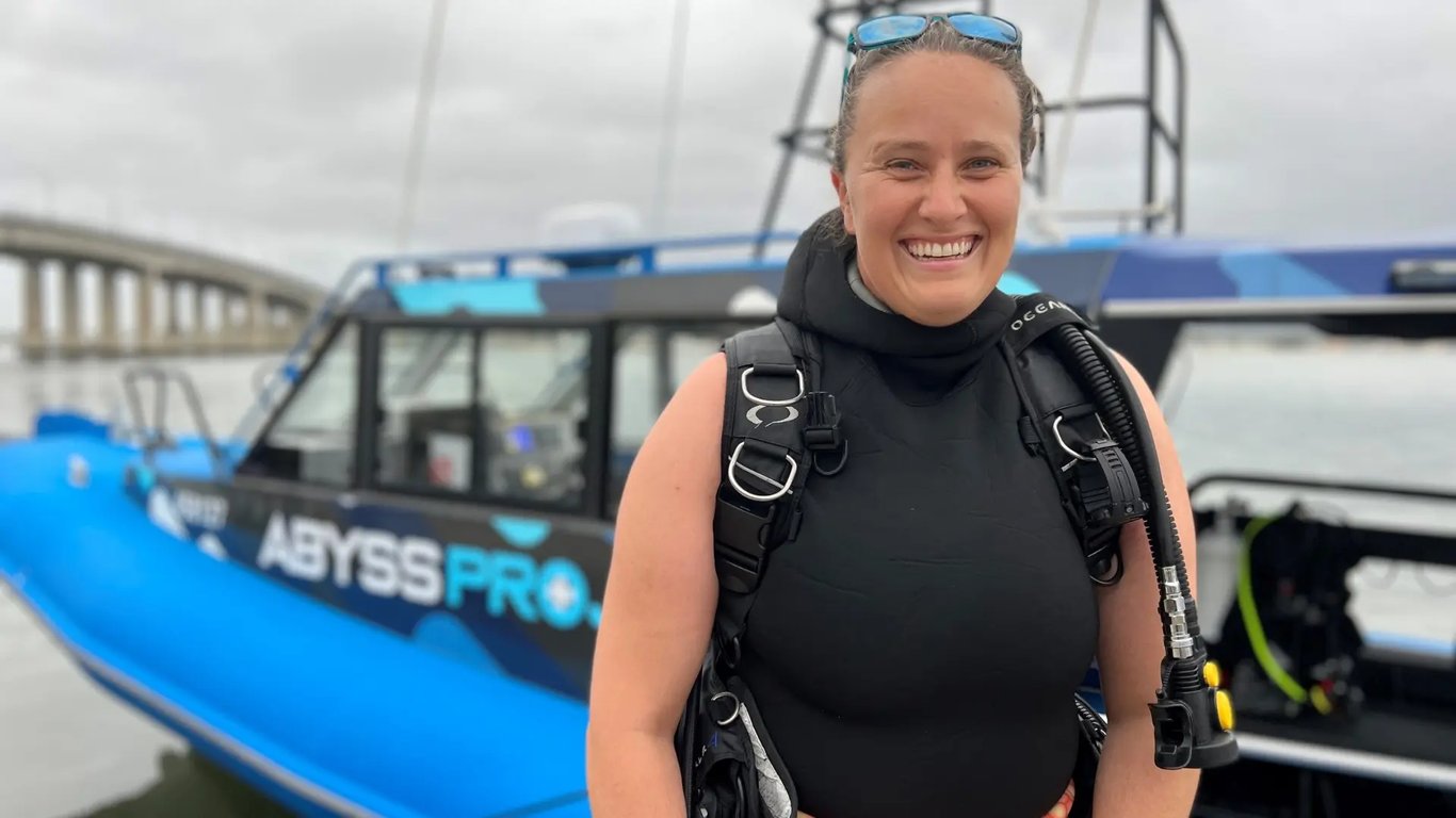 Smiling scuba diver in front of the Abyss Pro dive boat
