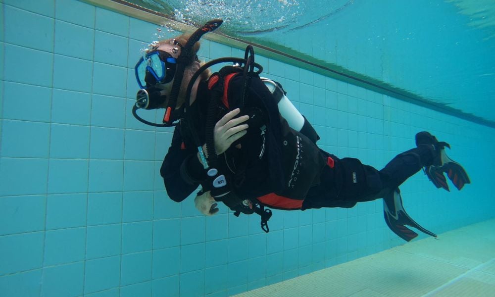An instructor guiding student in the PADI Open Water Diver Course, showcasing scuba gear and diving techniques.