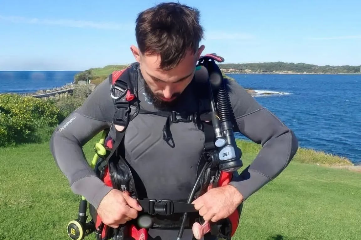 Diver wearing a BCD and regulator setup with a close‑up of a dive computer display