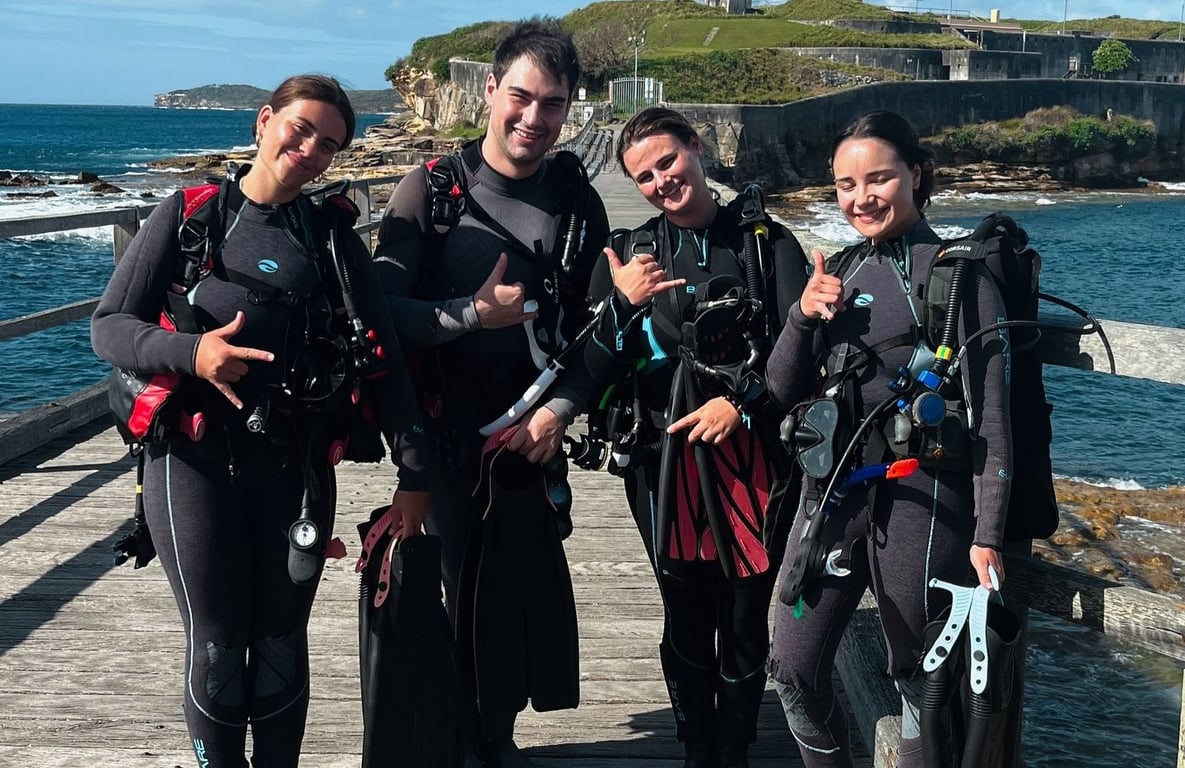 A group of newly certified divers joyfully celebrates their successful completion of an ocean dive training session, showcasing their enthusiasm and confidence after completing their PADI open water course. 
