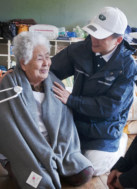 慈濟環保毛毯由回收寶特瓶再製成，具備輕柔保暖特性，廣泛用於國際緊急援助、難民安置，溫暖無數受苦的心靈。日本 311 大地震，慈濟志工前往避難所發放，親手為老奶奶披上毛毯。