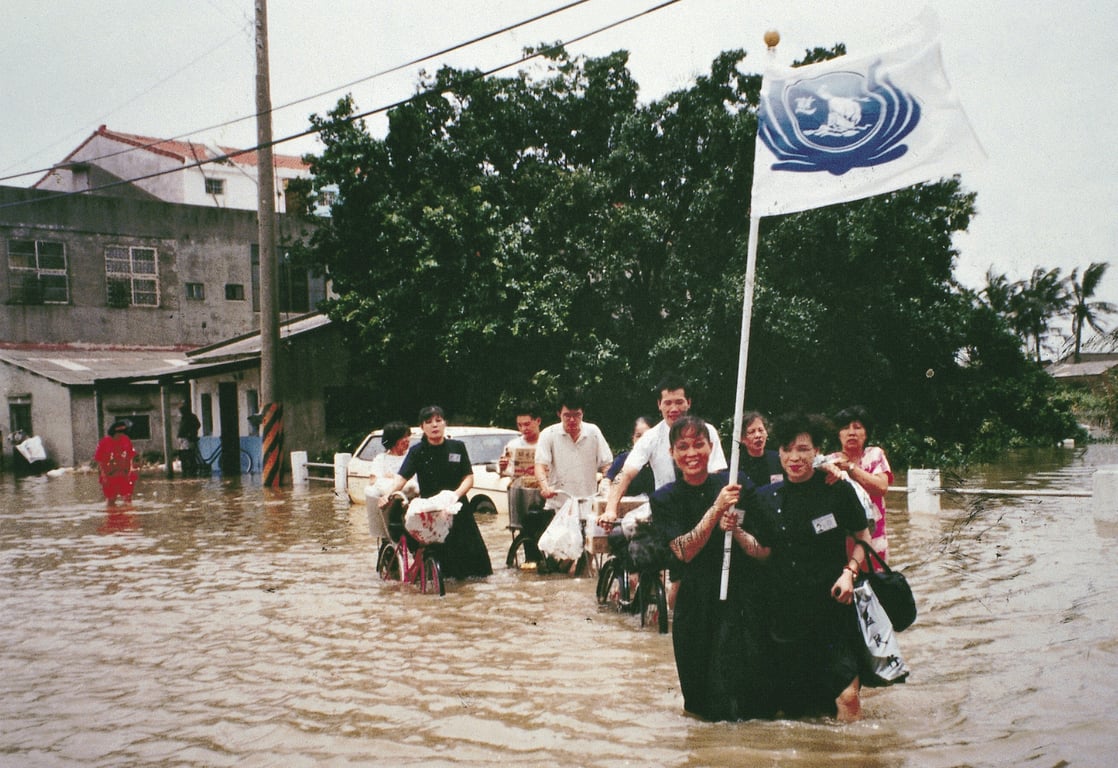 1996 年賀伯風災布袋鎮嚴重淹水，慈濟志工涉水進入災區發放熱食。昔日賀伯颱風的賑災行動路途遙遠且交通受阻，慈濟志工集結艱難，此經驗成為契機，催生落實全臺志工社區化模式，讓社區平時儲備人力、物力，災時就地動員、加速應變。