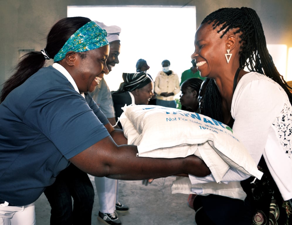 慈濟深耕非洲三十多年，長期落實「自助助人」理念，讓當地人理解愛與慈悲。如今本土志工已發展至數千人，他們翻山越嶺幫助苦難貧病。圖：「藍天白雲」的志工身影，恭敬列隊彎腰奉上救濟物資，幫助受災民眾度過難關，所有人都為這份祝福露出喜悅的笑容。