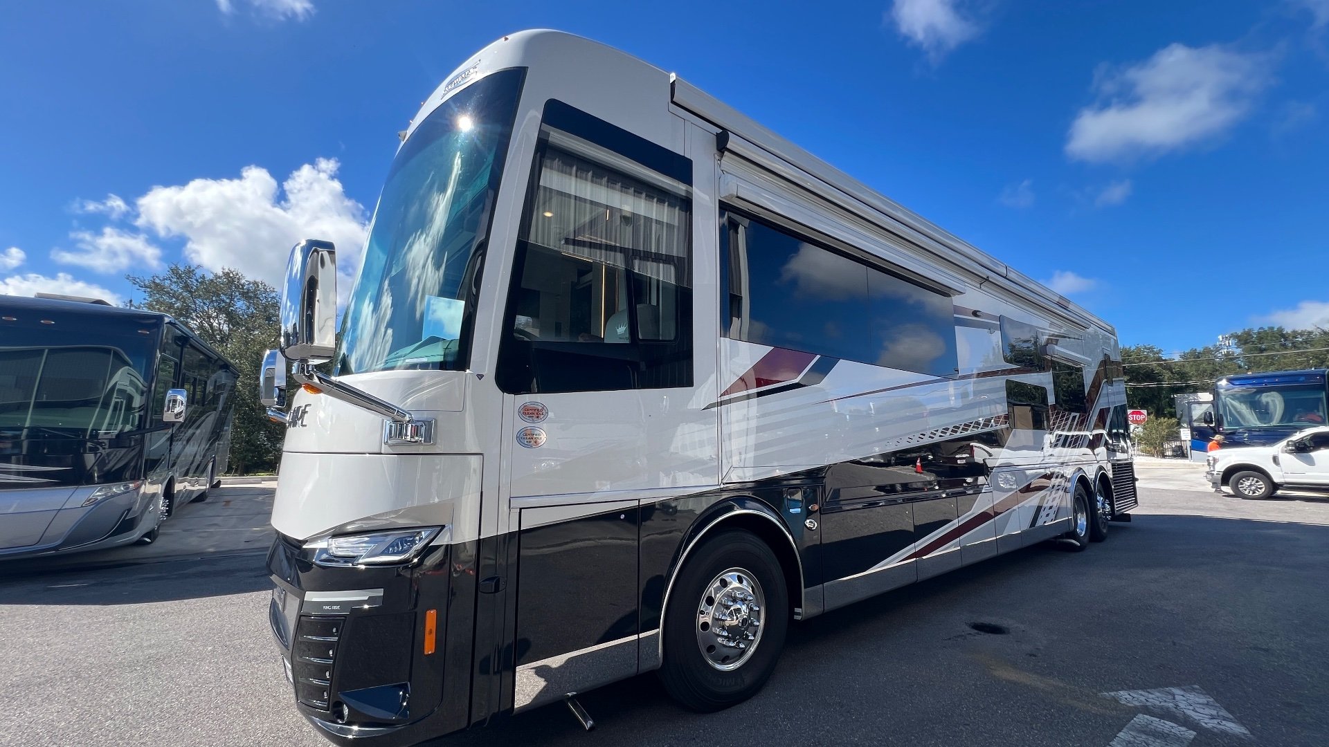 2025 Newmar King Aire 4558 — Visible exterior side and front of the motorhome, including windows, body, wheels, and awning