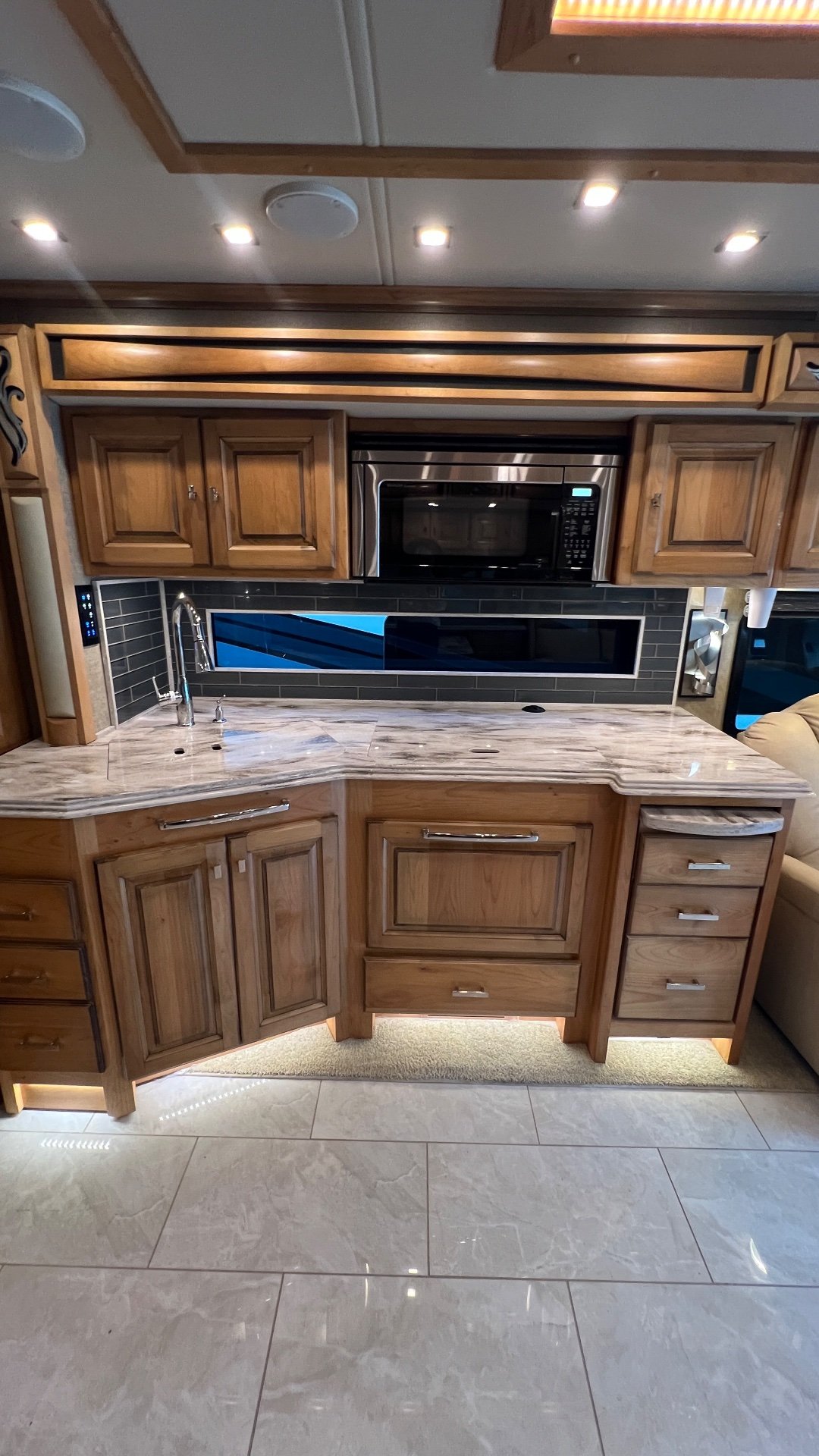 2019 Tiffin Phaeton 40 IH — Motorhome kitchen counter with sink, faucet, microwave, backsplash, drawers, and illuminated lower cabinetry