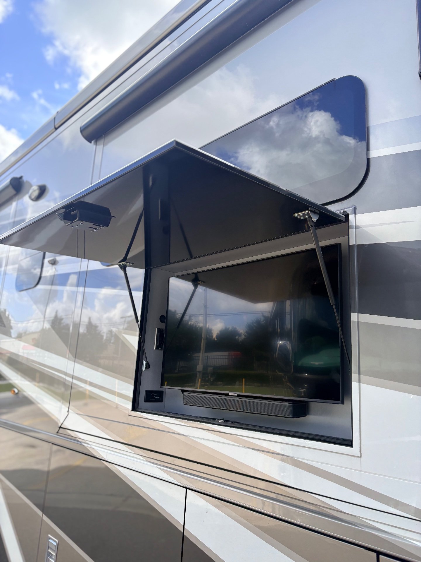 2025 Newmar Dutch Star 4369 — Exterior side wall of the RV with an opened outdoor entertainment compartment and television