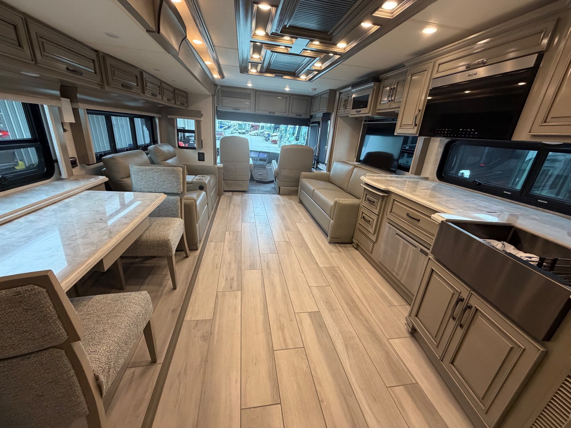 2025 Newmar Dutch Star 4369 — Class A RV interior overview with kitchen cabinetry, lounge seating, dining table, and cockpit beyond