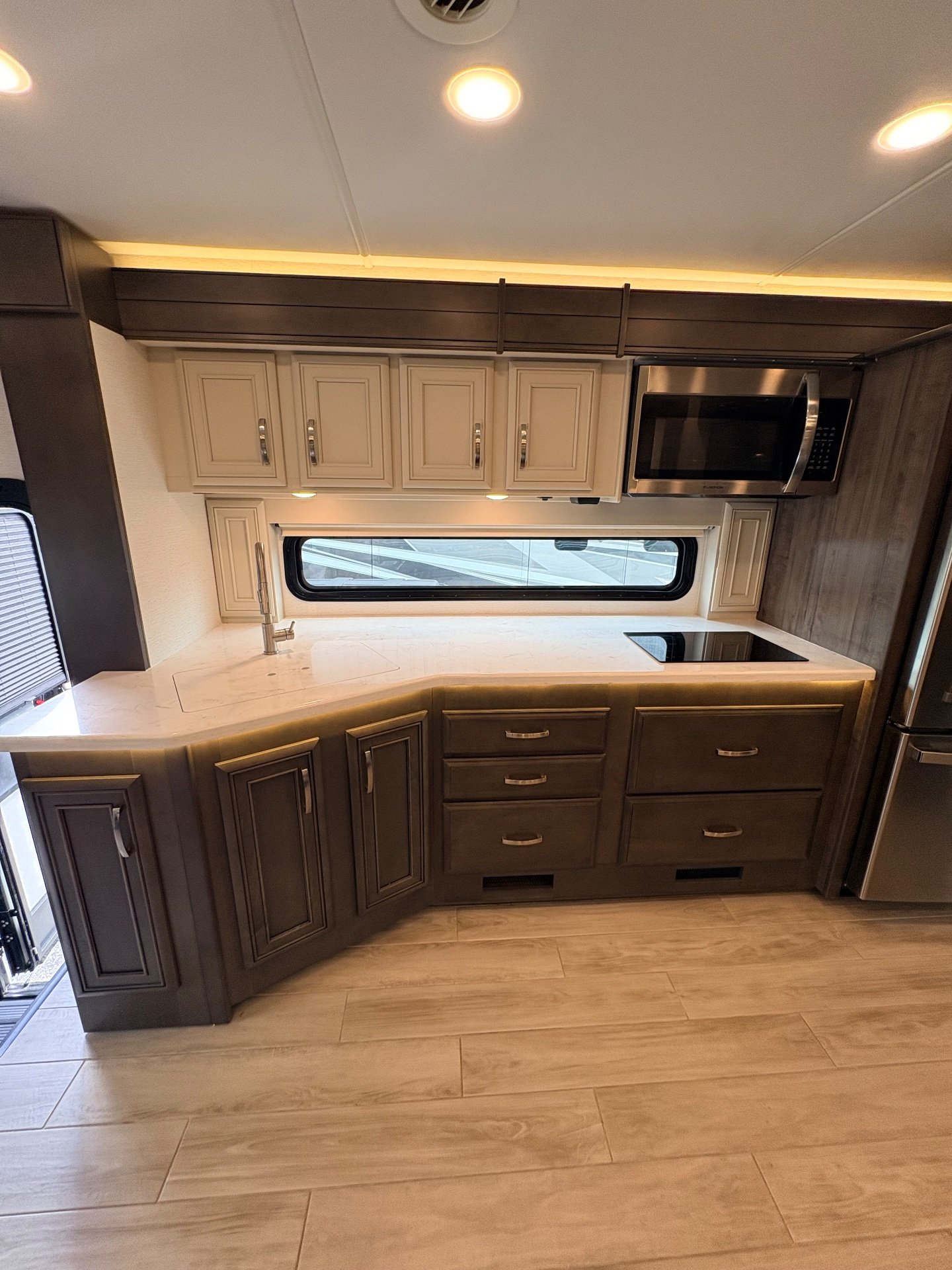 2025 Entegra Coach Accolade XL 37L — Motorhome kitchen with L-shaped countertop, sink, induction cooktop, microwave, drawers, cabinets, and refrigerator