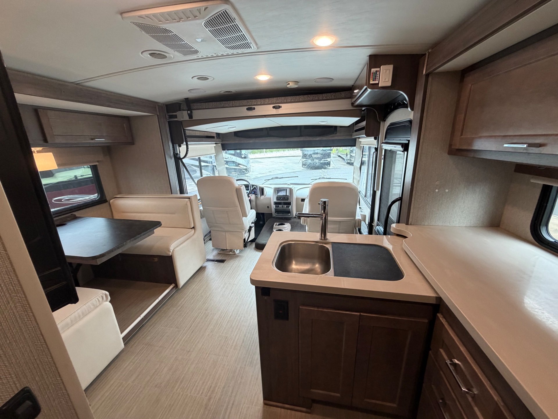 2021 Winnebago Adventurer 27N — Class A kitchen sink and counters overlook the dinette and driver cockpit in a broad interior overview