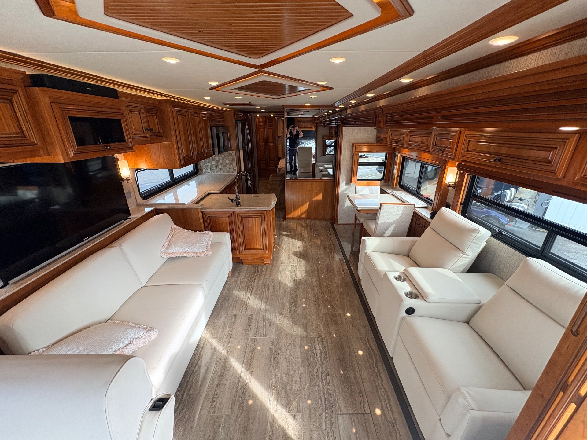 2020 Newmar Dutch Star 3717 — Class A lounge with sofa, recliners, television, adjacent kitchen island, and dinette visible along the central aisle