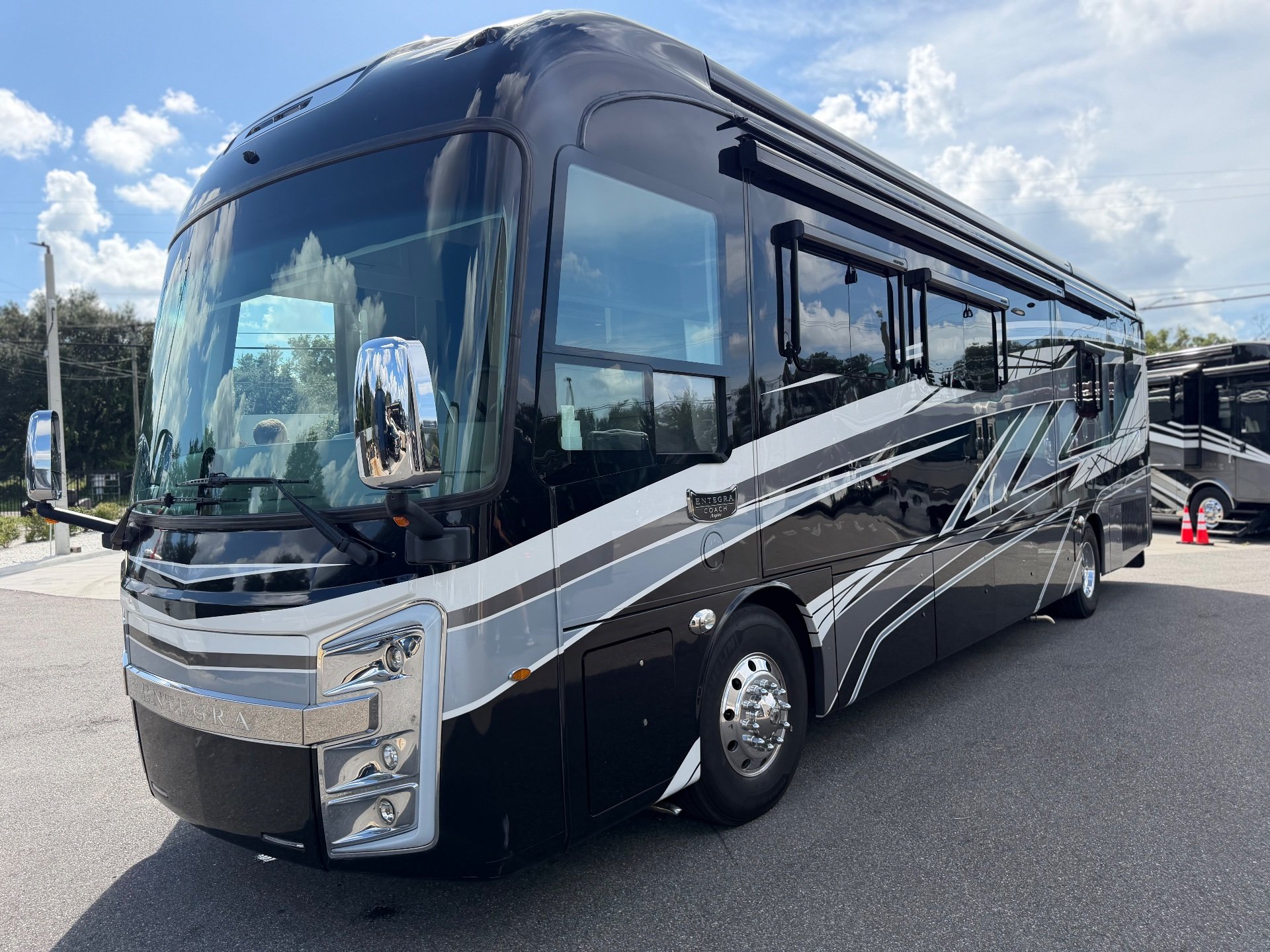 2023 Entegra Coach Aspire 40P — The motorhome's front and side exterior with body graphics, windows, wheel, and exterior compartments