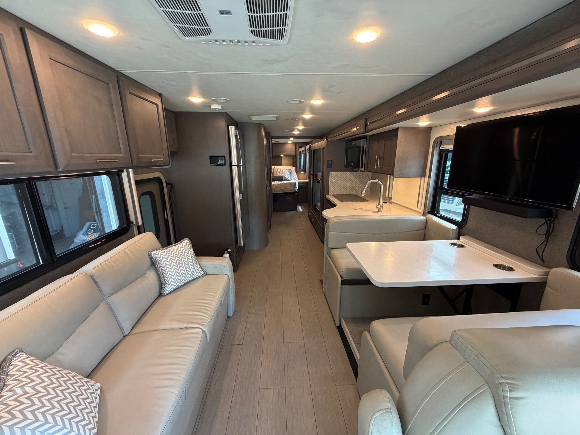 2022 Thor Motor Coach Palazzo 33.5 — Class A interior overview showing sofa, dinette, kitchen counters, refrigerator, and rear bed along the central aisle