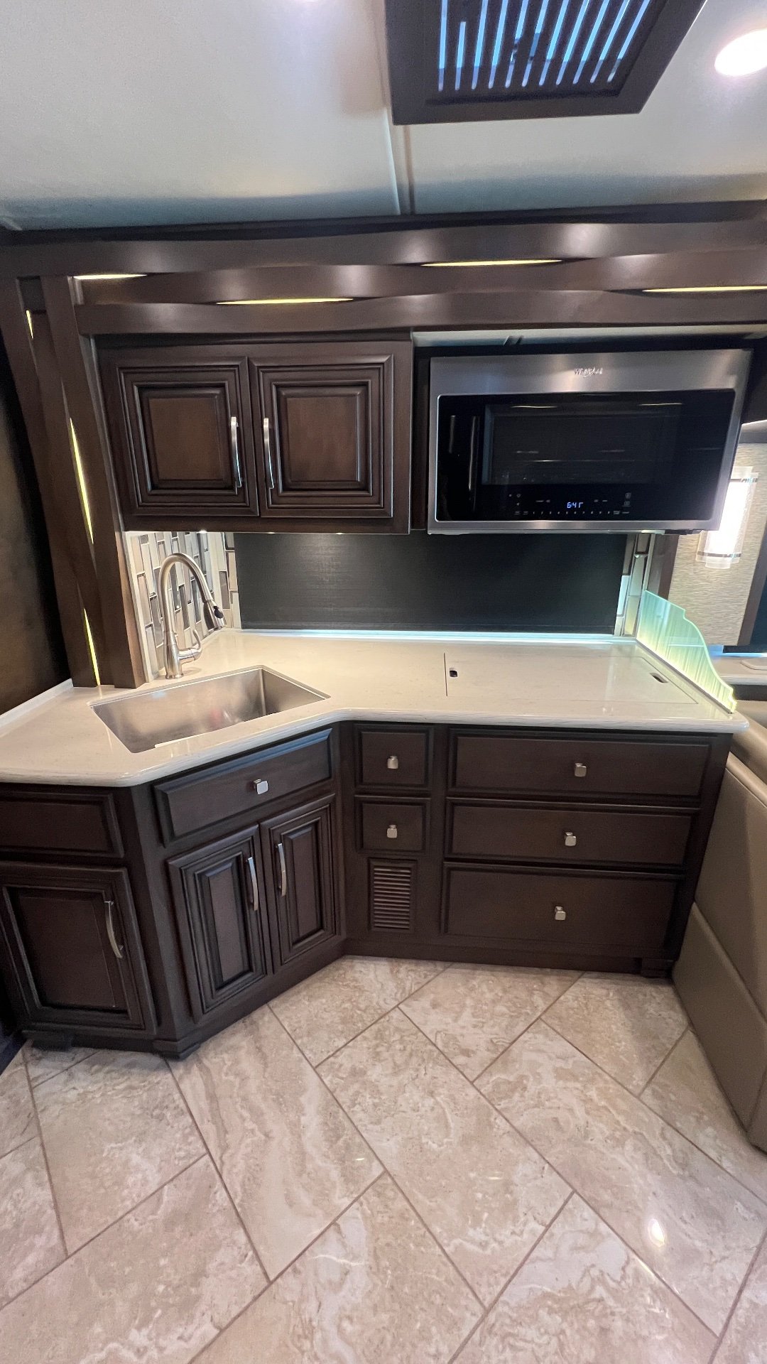 2021 Newmar New Aire 3541 — Motorhome kitchen with stainless sink, high-arc faucet, microwave, countertop, drawers, and dark cabinetry
