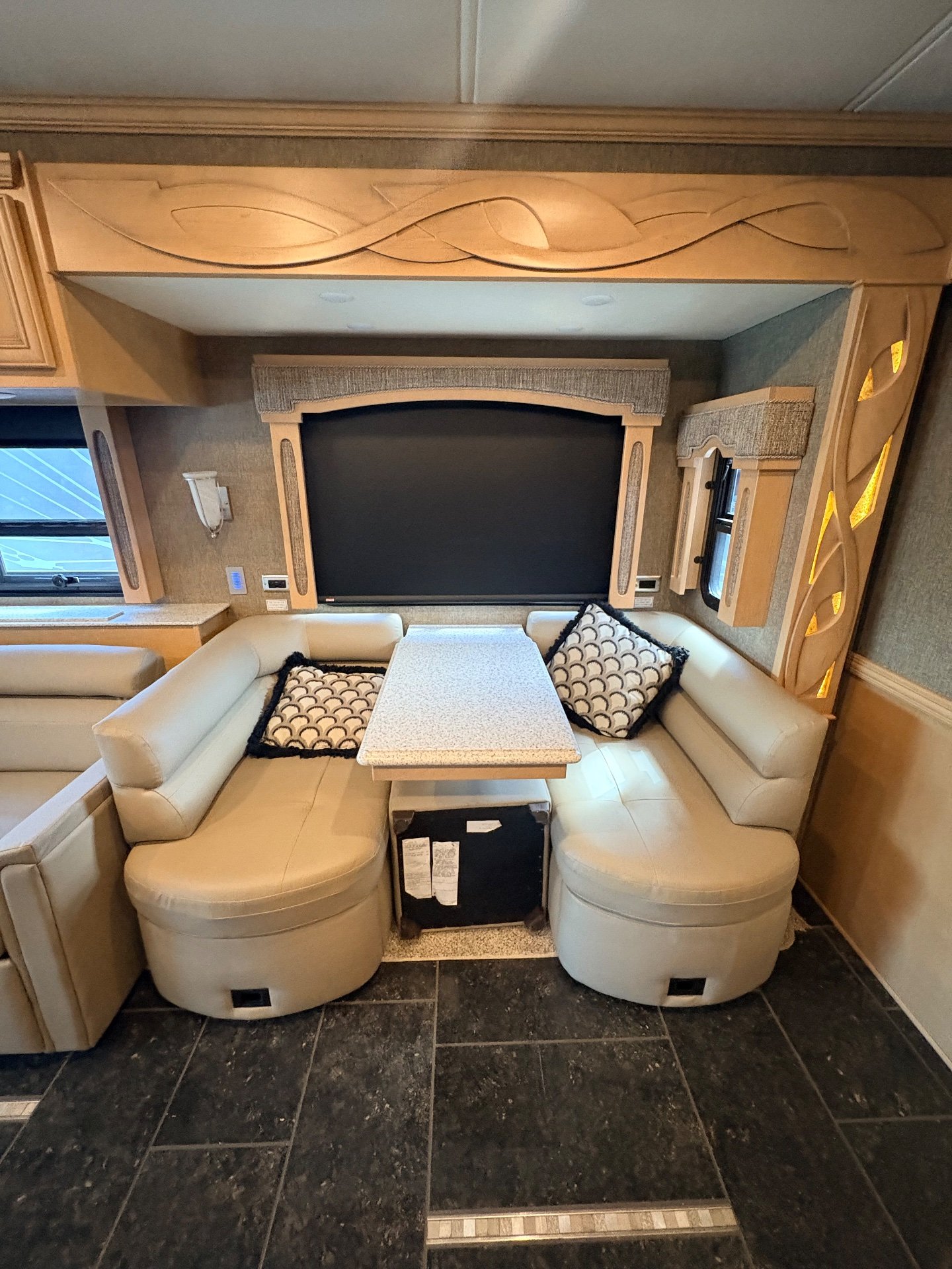2019 Newmar Ventana 4002 — U-shaped dinette with tabletop and television, with adjacent sofa visible at the left