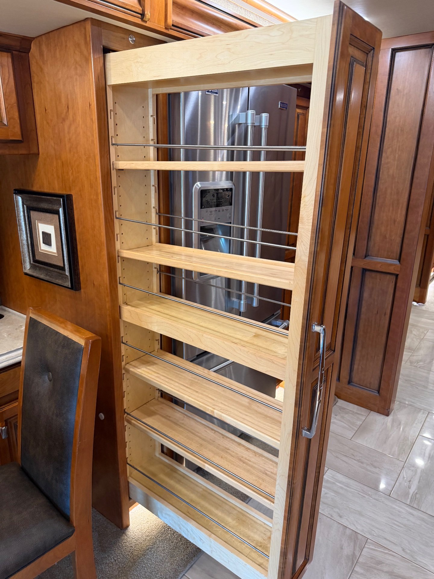 2017 Tiffin Allegro Bus 45 OPP — Open pull-out pantry beside refrigerator, with a dining chair and kitchen cabinetry visible nearby