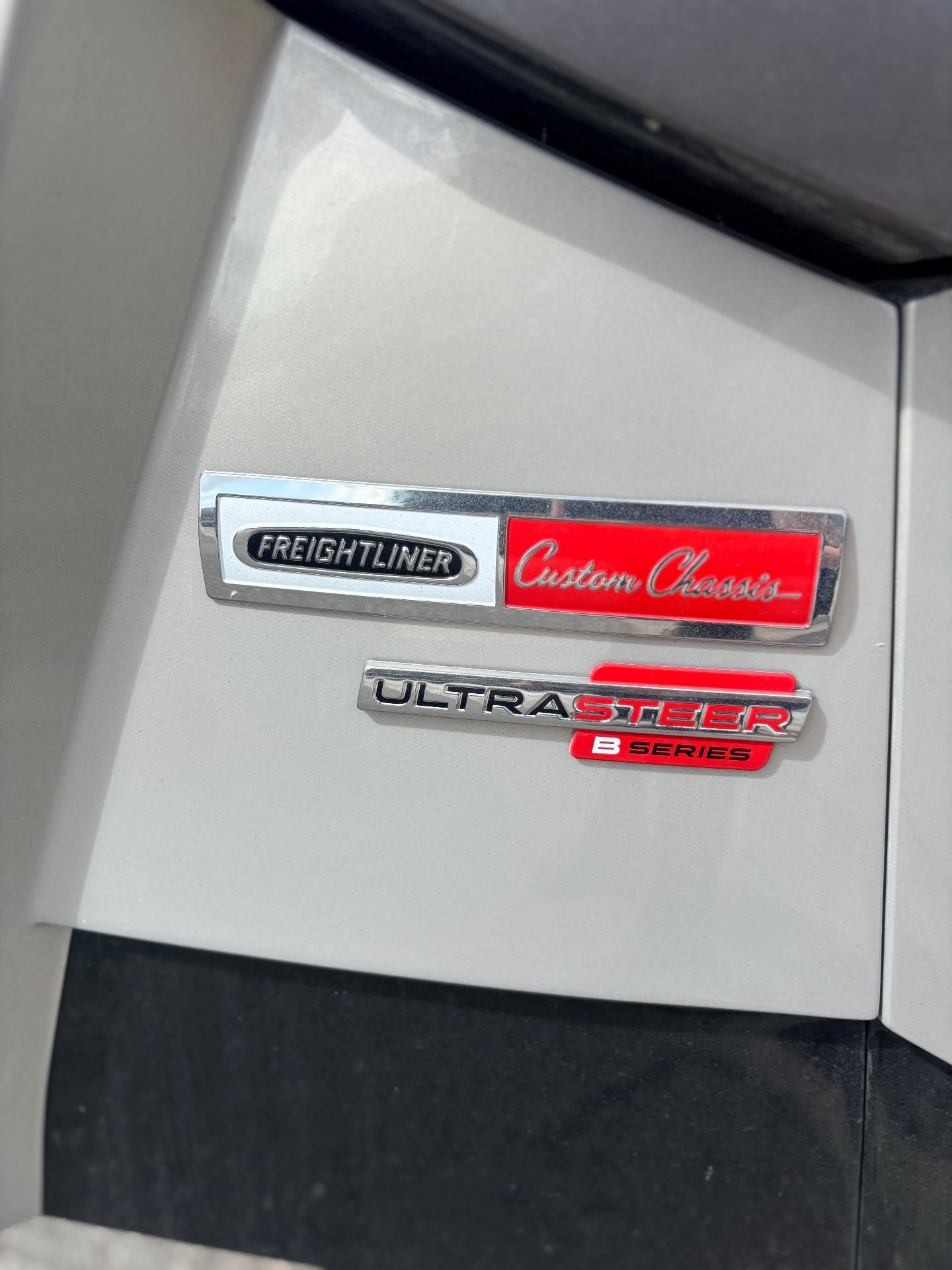 2025 Newmar Dutch Star 4369 — Close-up visibly shows exterior-installed Freightliner Custom Chassis and UltraSteer chassis badges