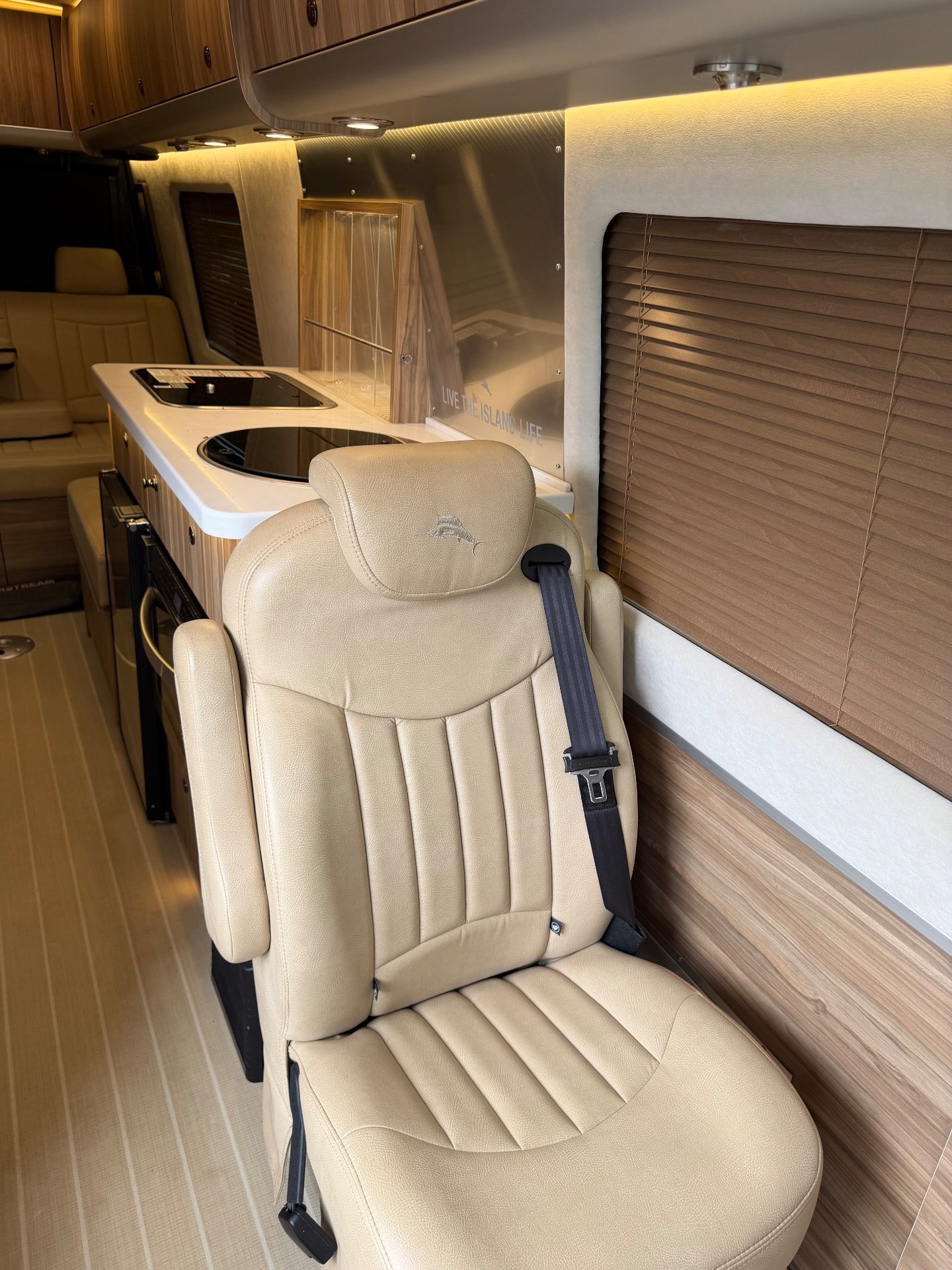 2020 Airstream Interstate 24GL 4WD — Galley counter with two covered cooktops and cabinetry sits beside a captain’s chair and rear lounge seating