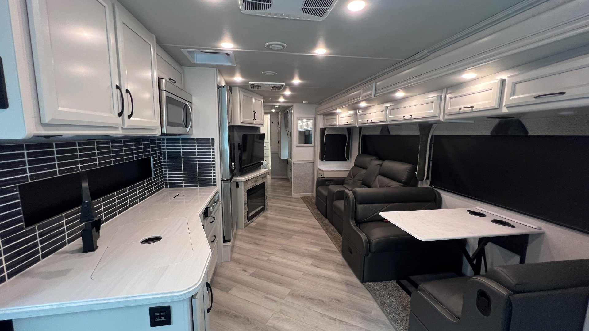 2024 Fleetwood Bounder 35K — Class A motorhome living area with recliners, dinette, entertainment center, and adjacent kitchen counter and appliances
