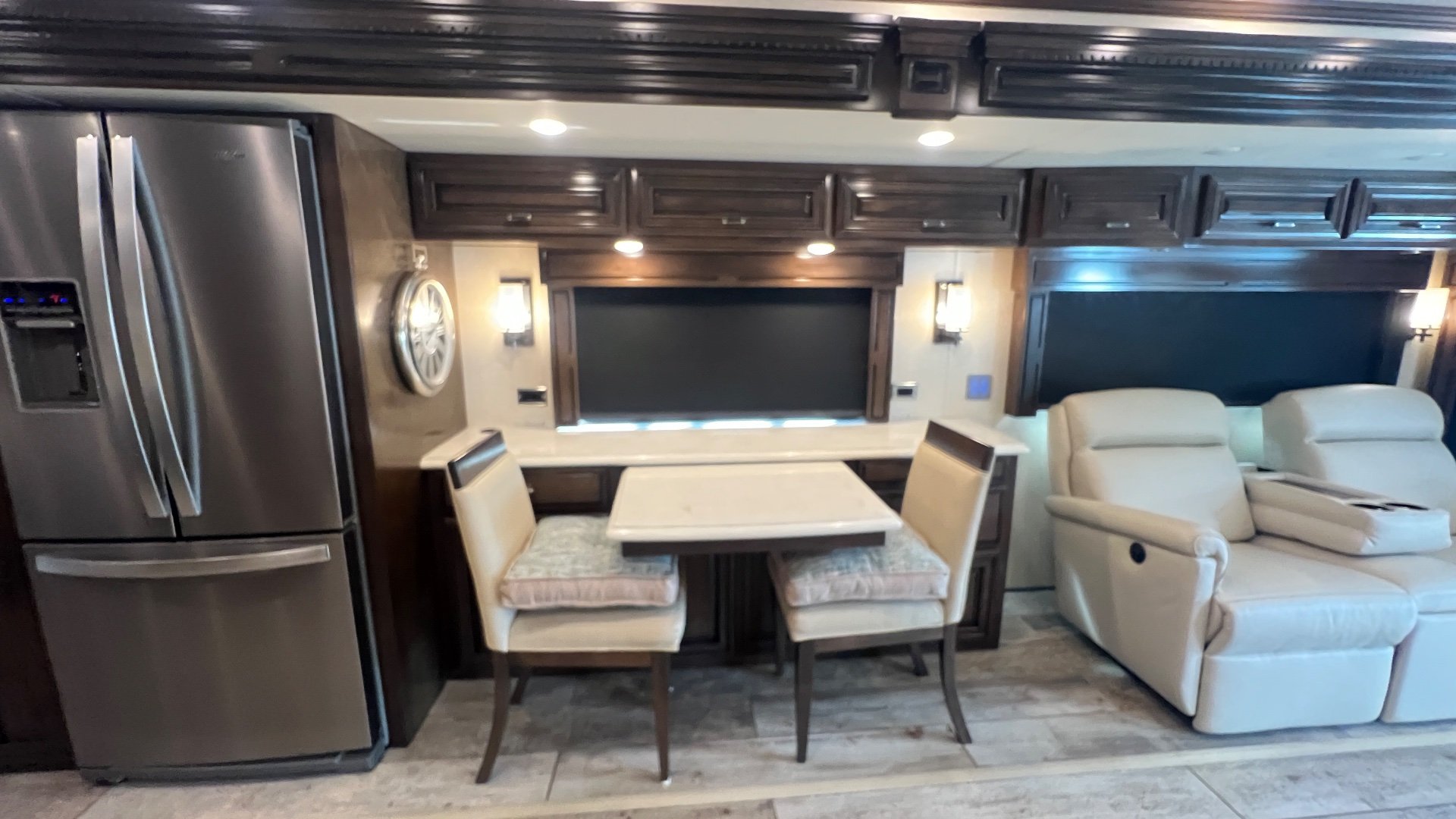 2020 Newmar Dutch Star 4328 — Dining table and chairs between a refrigerator and two reclining lounge seats with a large window and cabinetry