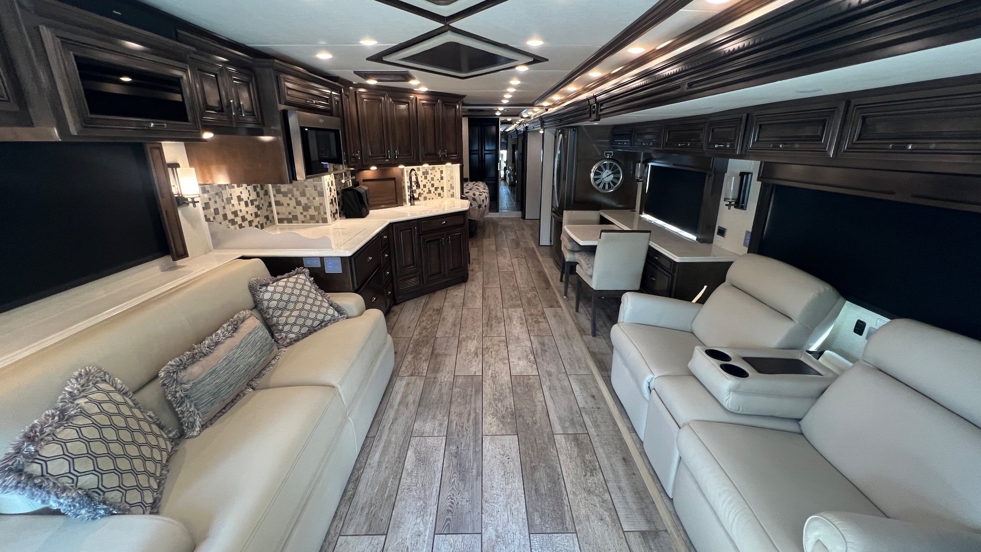 2020 Newmar Dutch Star 4328 — Wide Class A interior overview showing sofa, recliners, kitchen counters, dining table, cabinetry, and central aisle