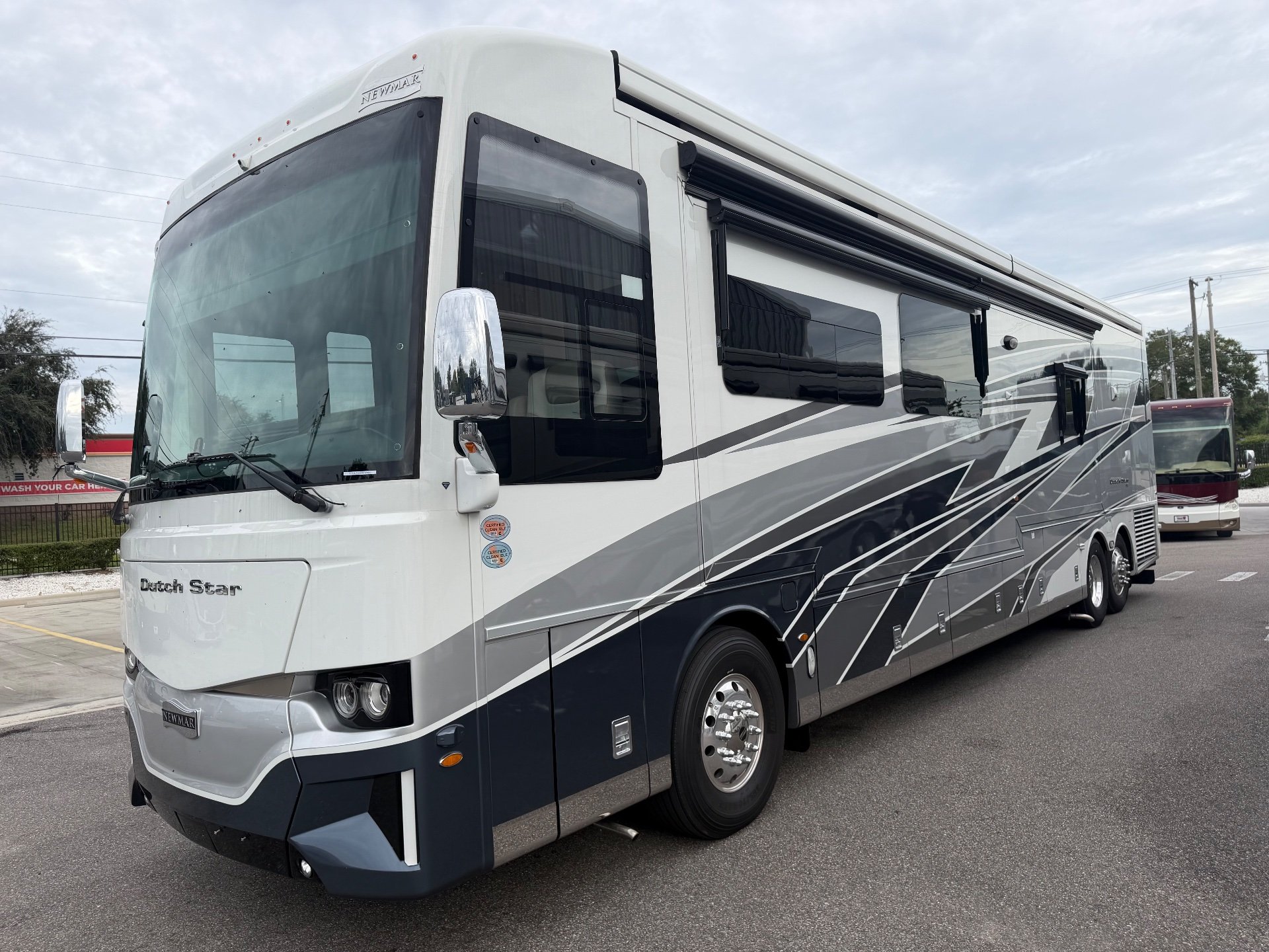 2025 Newmar Dutch Star 4369 — Visible front-side exterior view of the RV shell, side windows, awnings, wheels, and exterior panels