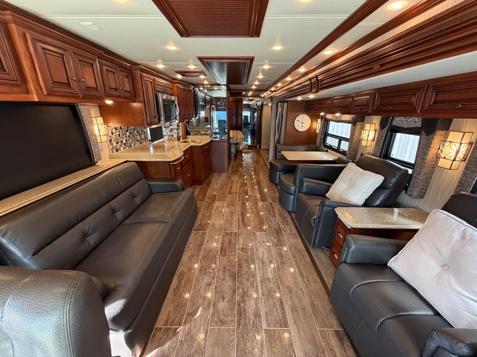 2017 Newmar Dutch Star 4369 — Class A living area with leather sofas and recliners, adjacent kitchen counters, and a rear dinette along the central aisle