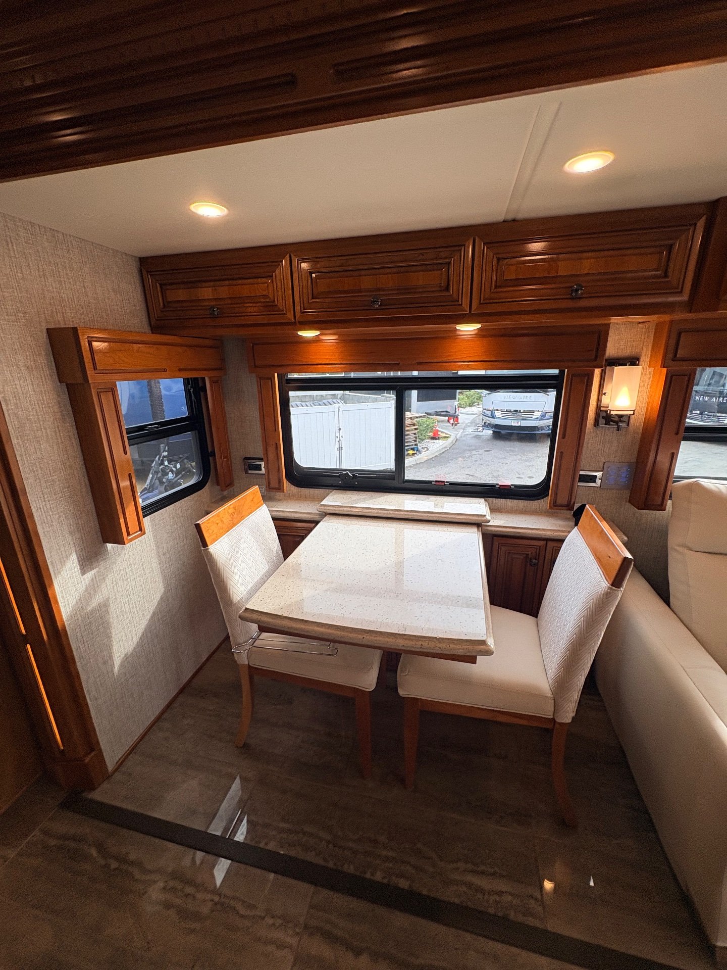 2020 Newmar Dutch Star 3717 — Freestanding dinette with two upholstered chairs, tabletop, window, and surrounding overhead and base cabinetry